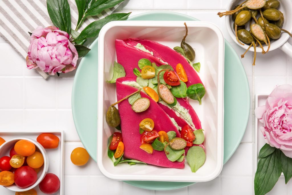 Buraczane naleśniki z pastą z awokado i ricotty, owocami kaparowca, pomidorkami i roszponką